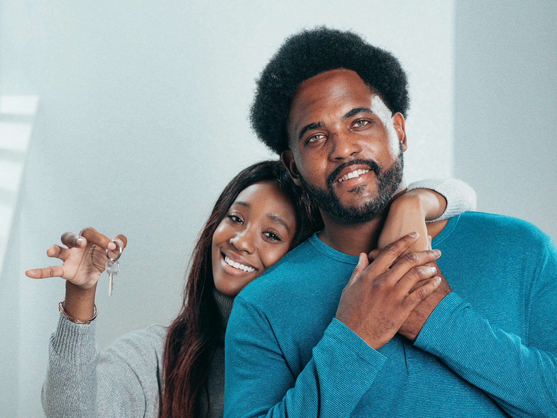 Joyful couple proudly holding keys to their new home, symbolizing fresh beginnings.