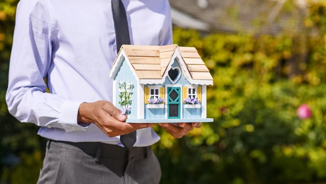 a person holding a miniature wooden house