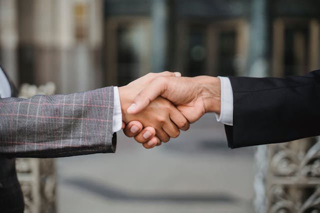 two people shaking hands outside