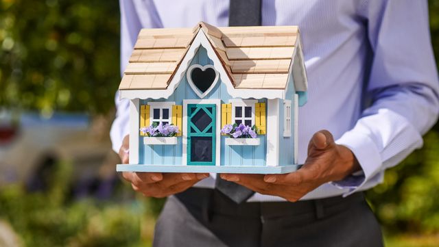 a person holding a decorated wooden house model